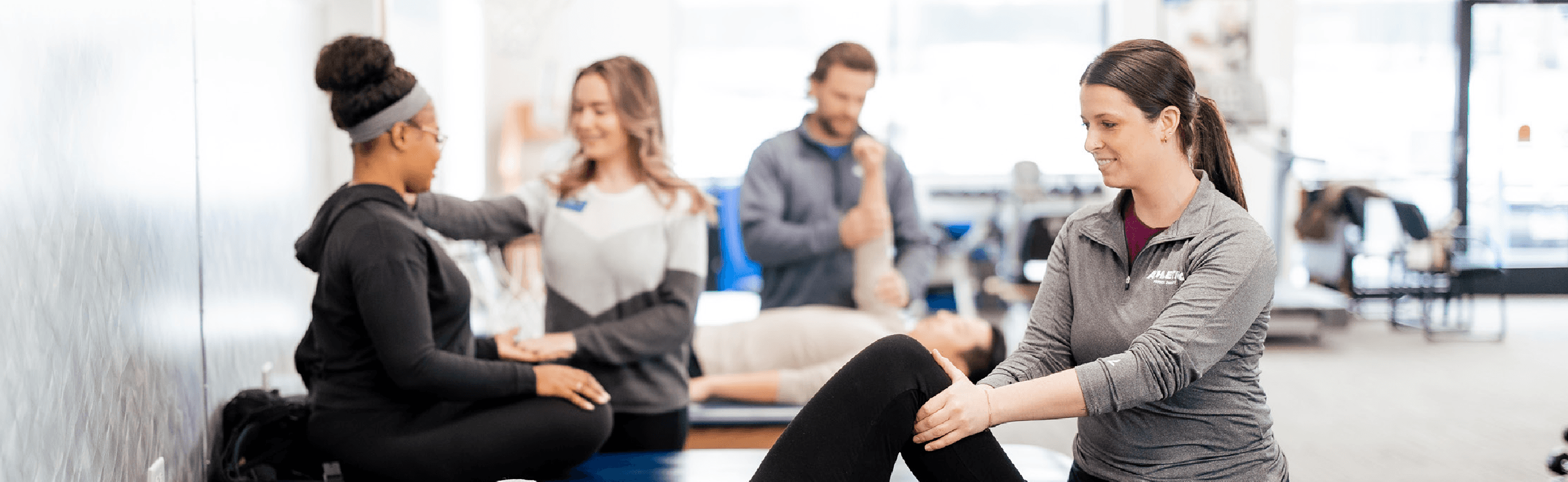 Physical therapists and patients working together in a bright rehabilitation gym with exercise mats and equipment